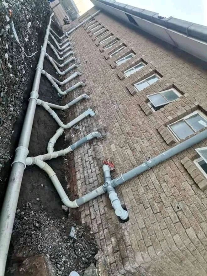 Row of downpipe connections along a brick wall