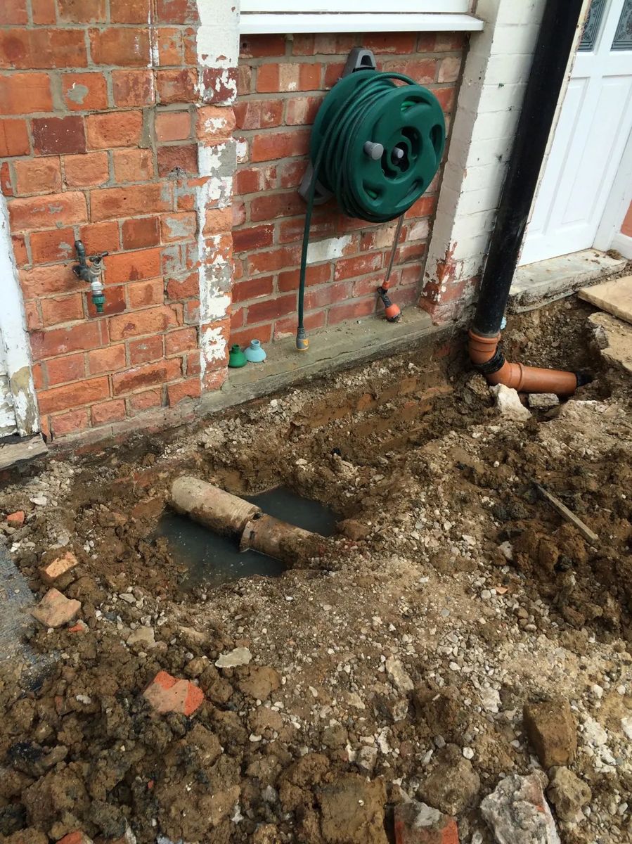 Old pipe section exposed in a dug-out area beside a wall